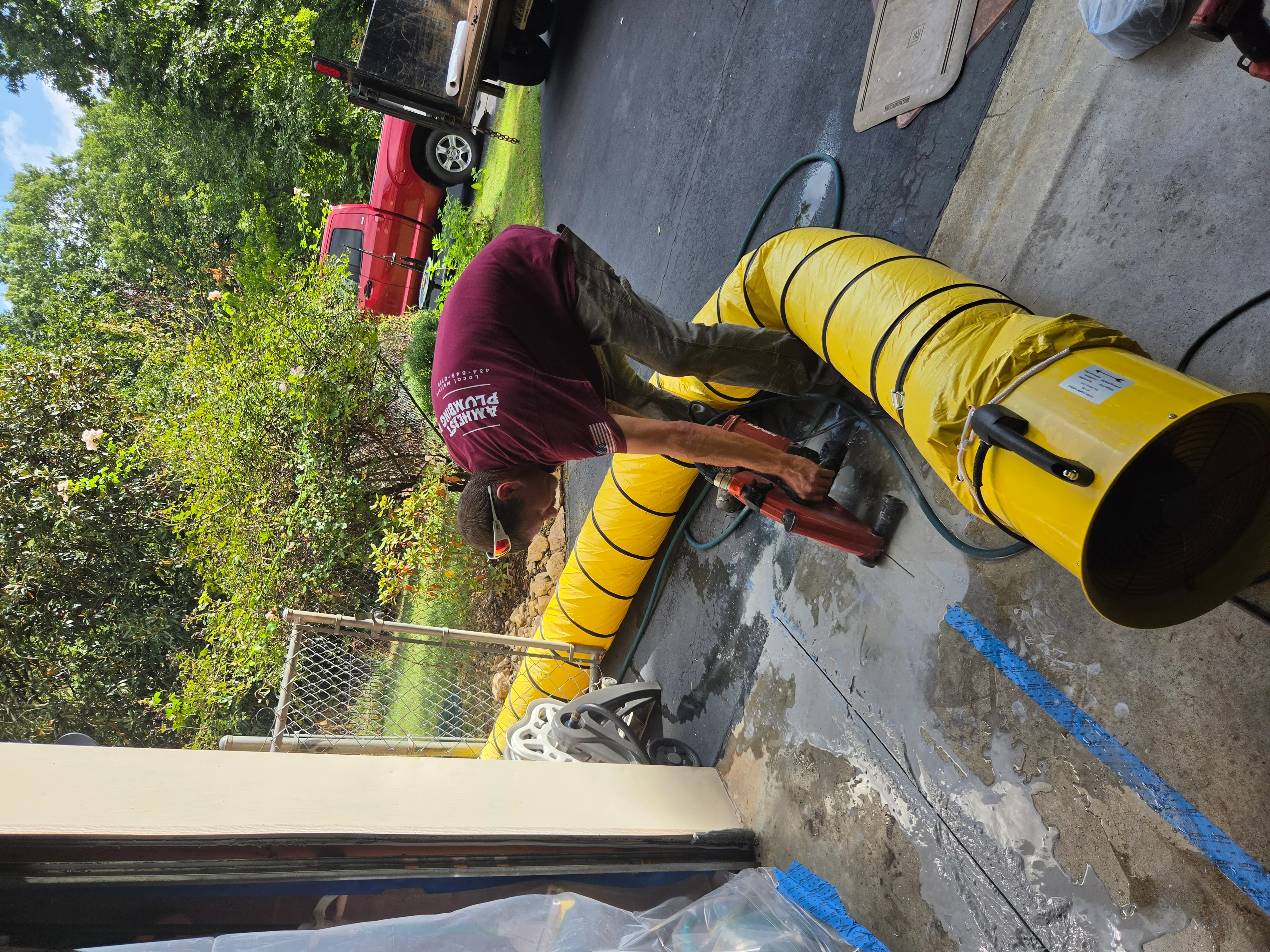 Technician operating yellow sewer camera equipment with flexible tubing for drain inspection